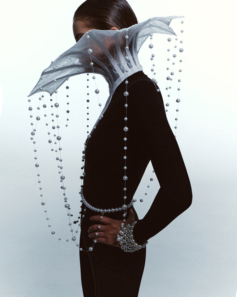 Piece of neck jewellery made of white lace and pearls on a model dressed in black