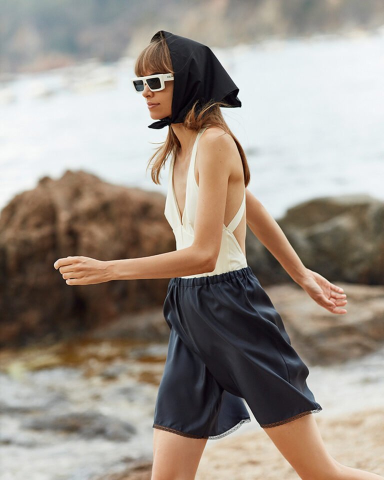 Model in black and white outfit is walking near the seashore