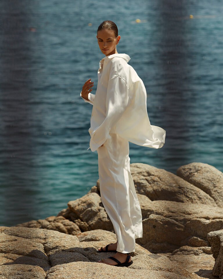 Fashion model wearing white is standing on the rocks