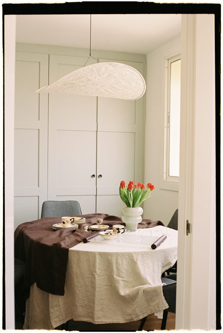 Dining table with a white ceiling lamp hanging over it.