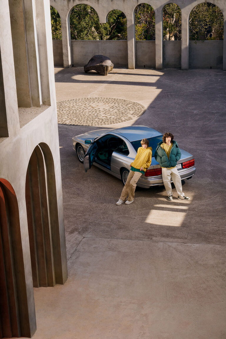 Two young people in urban outfits leaning on a car