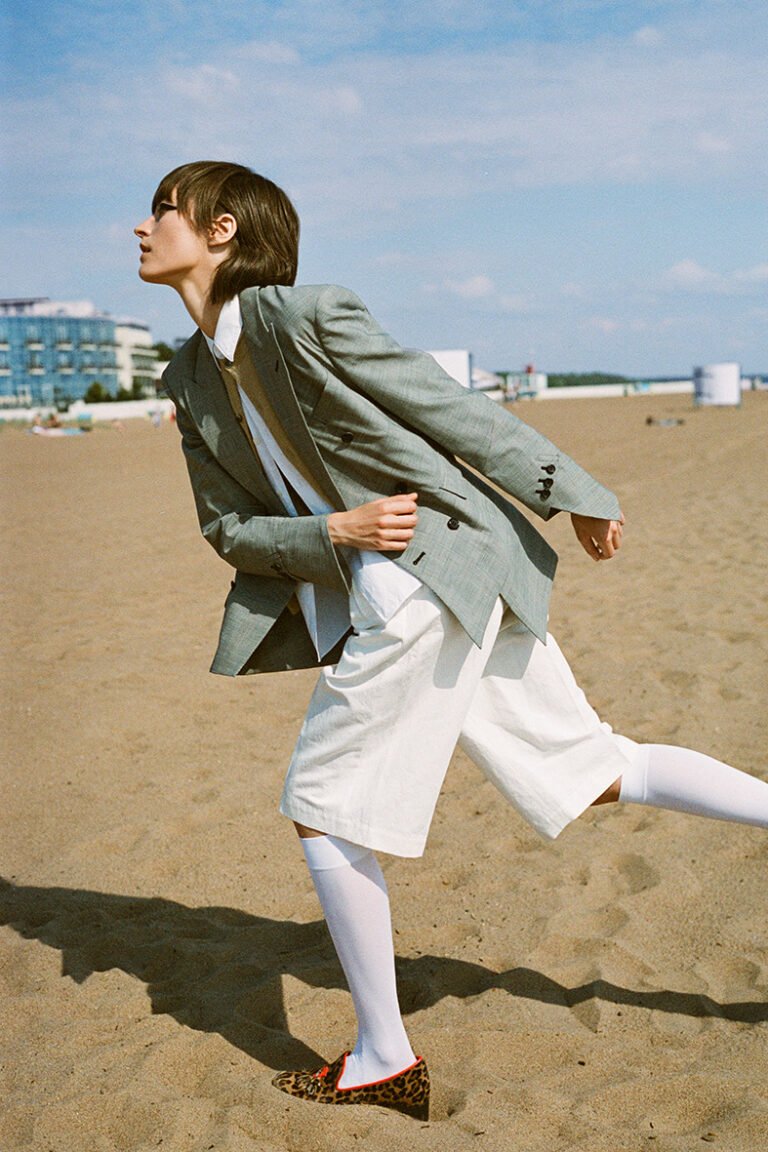 A model wearing a suit at the beach. COMME DES GARÇONS. Fashion photography.