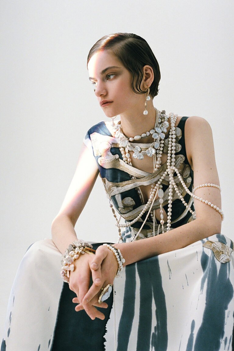 Sitting portrait of a model in a dress wearing pearl jewellery