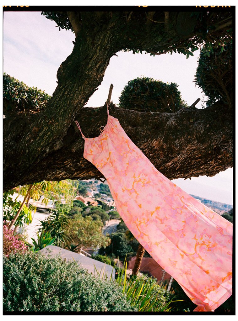 A pink dress hanging on a tree in the wind