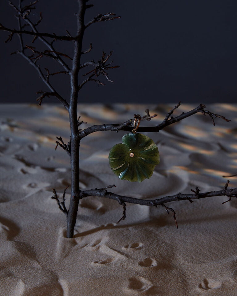 Piece of jewellery in a shape of green flower hanging of a little tree