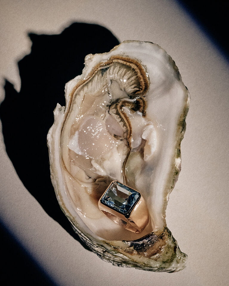 Photograph of a finger ring with a blue stone inside open oyster