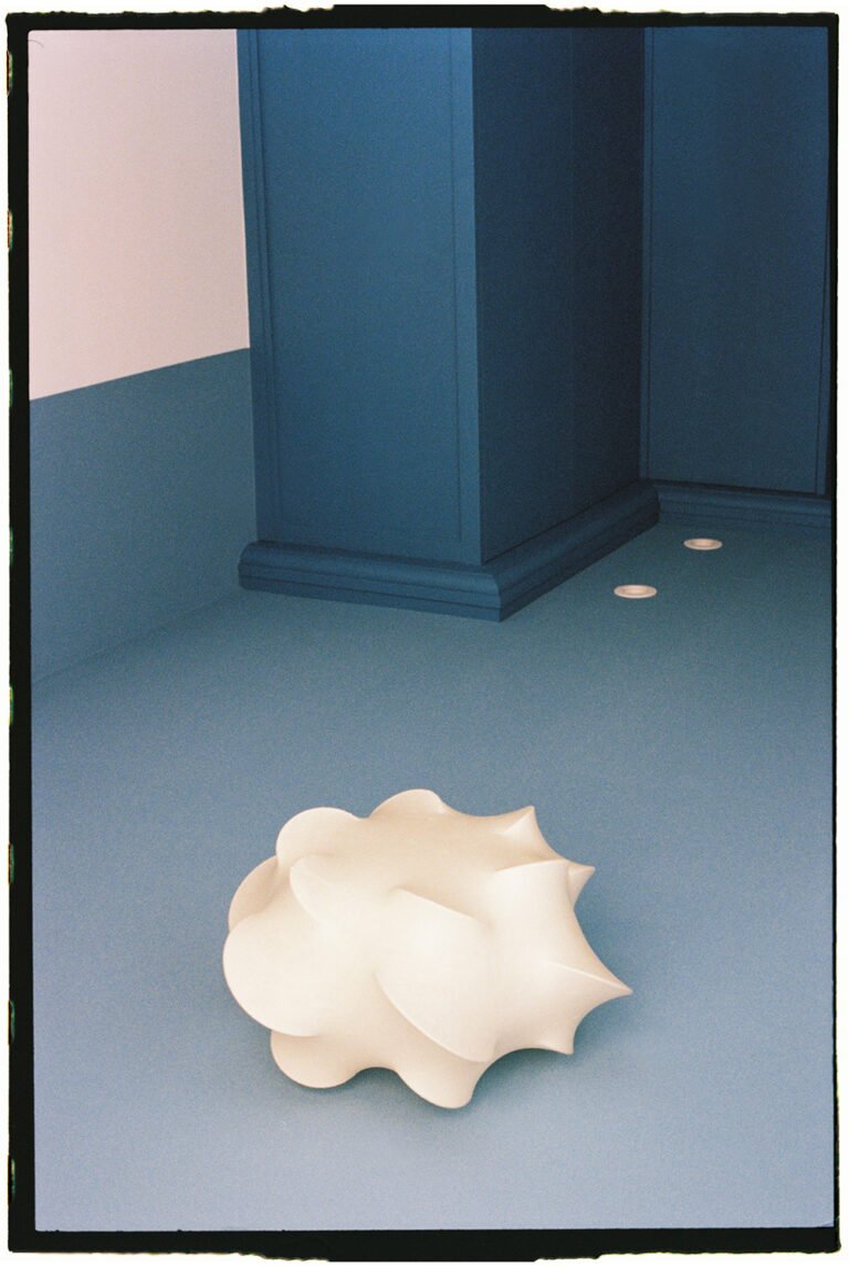 White lamp on the floor of a blue room.