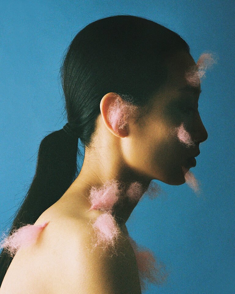 Photograph of a makeup model with bits of pink fluff on her skin