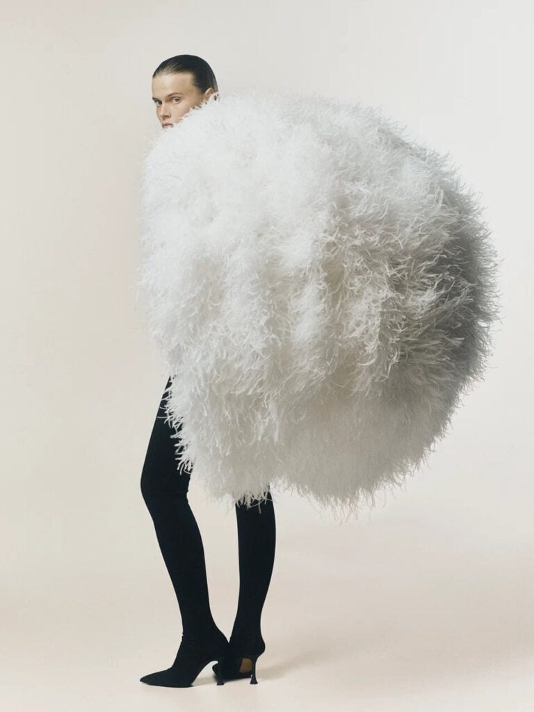 A fashion model half hidden with her fluffy white feathers outfit