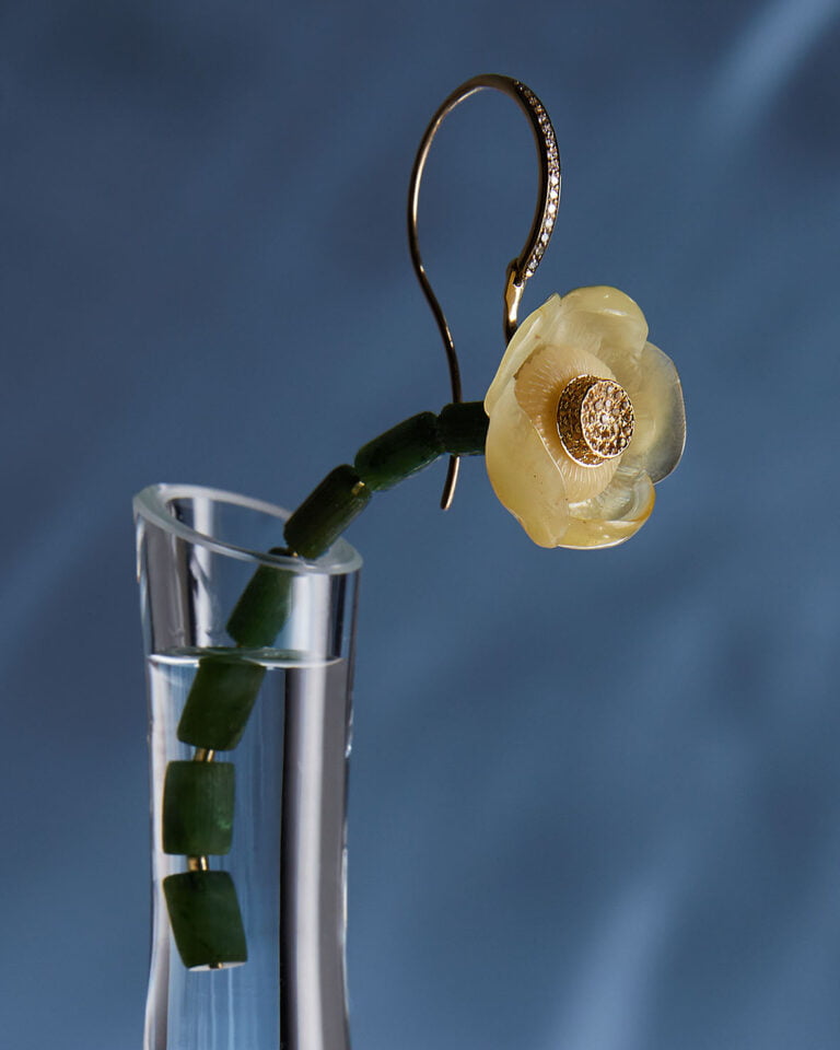 Close up of a flower shaped earring in a glass vase