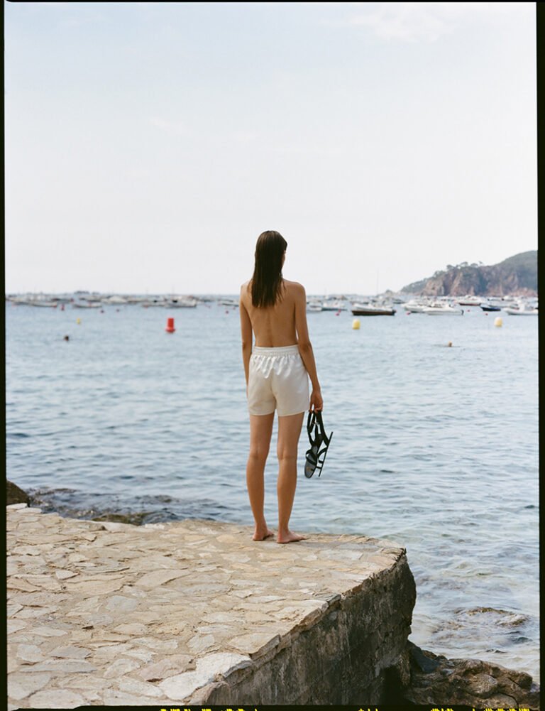 Model in white shorts is looking at the sea