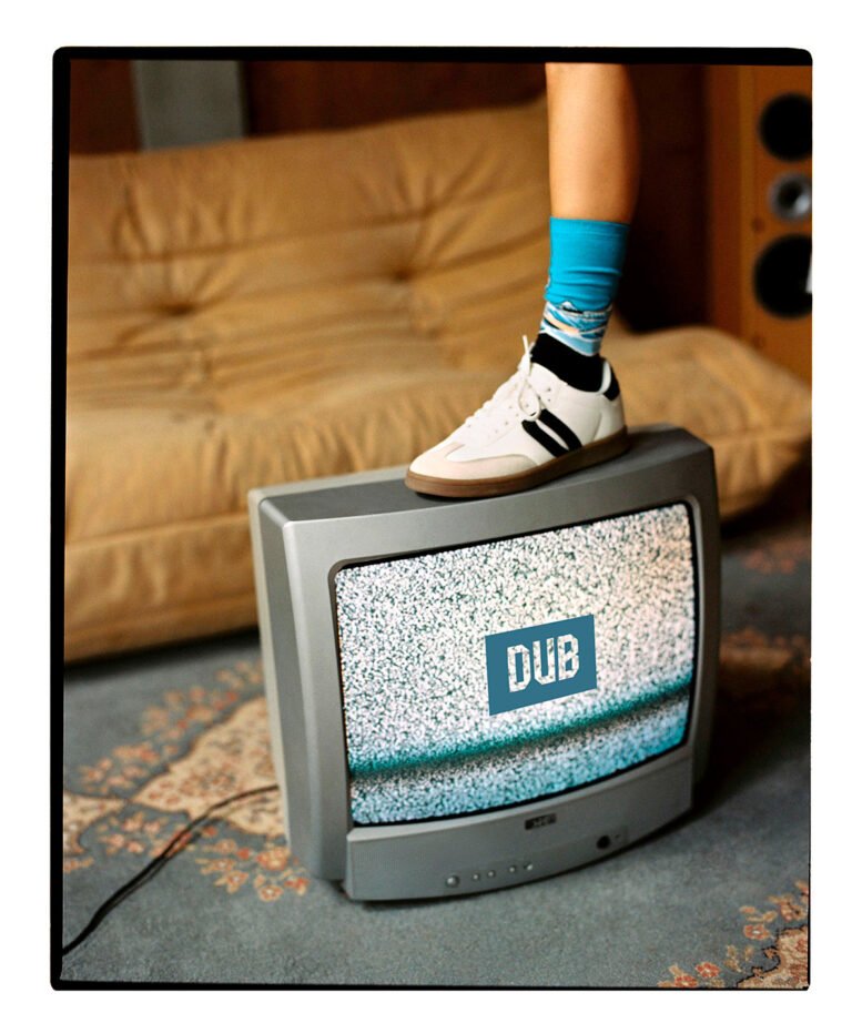 Foot in sneakers on top of an old tv