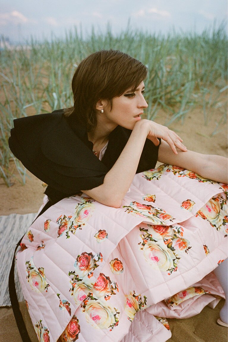 Fashion model is sittinig at the beach.