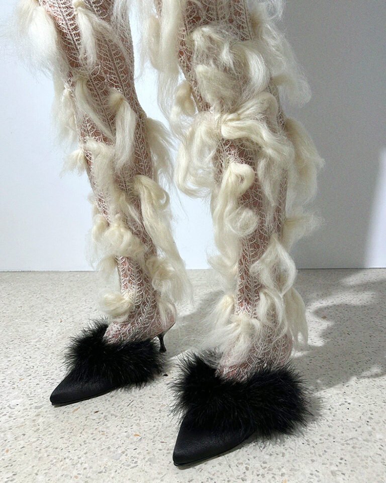 Woman's legs in tights with bits of white fluff and black mule shoes